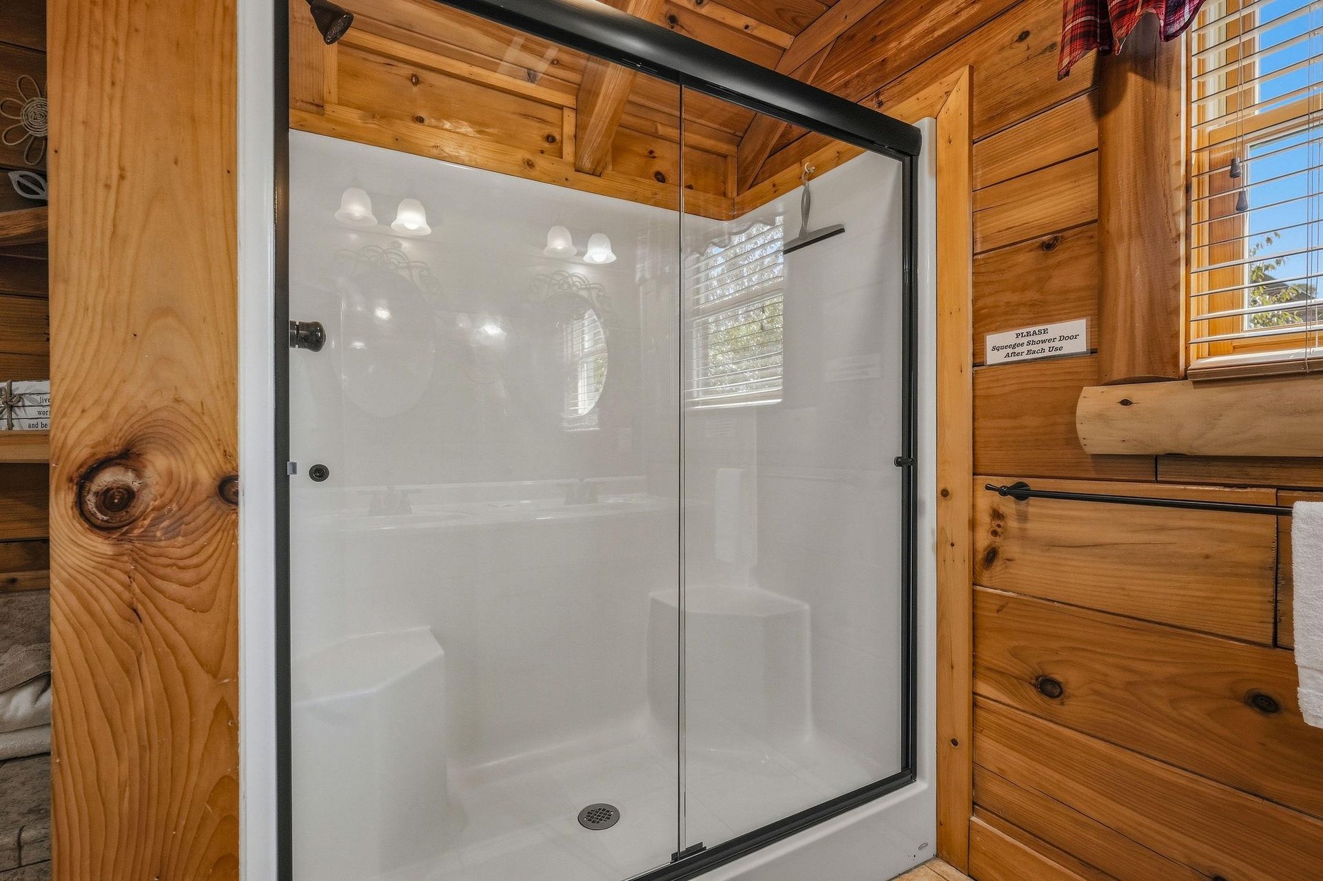 Step into your private walkin shower, framed by warm wood paneling and natural light streaming through cabin windows.