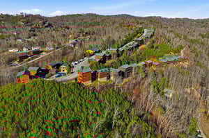 Aerial view of a mountain resort community nestled among rolling forested hills and winding roads.