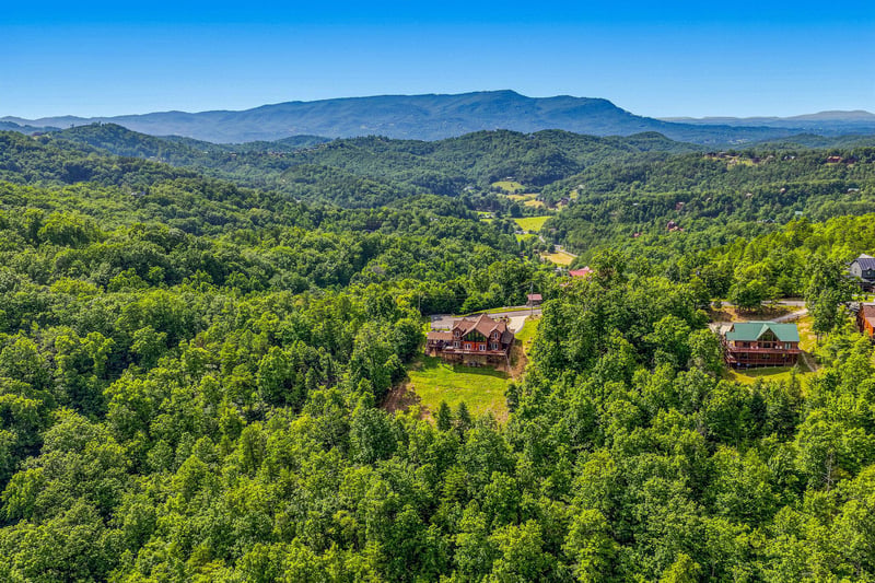 An expansive mountain landscape surrounds the property, with lush forested hillsides and distant peaks visible from this elevated vantage point in the area.