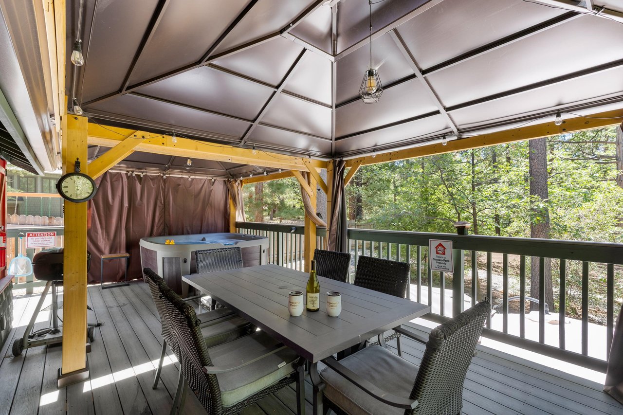 Spacious covered deck with a hot tub, outdoor dining table, and seating for 6.