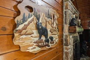 Rustic mountain charm greets you with custom wood carvings and a stacked stone fireplace—cozy craftsmanship that makes this cabin feel like your own alpine retreat.