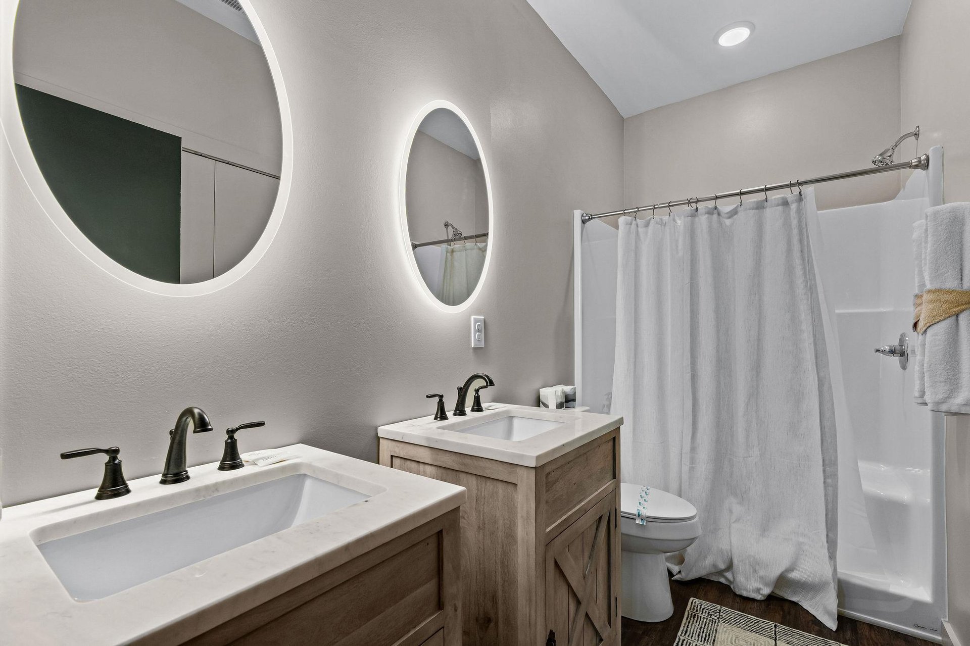 2 single vanities with lit round mirrors