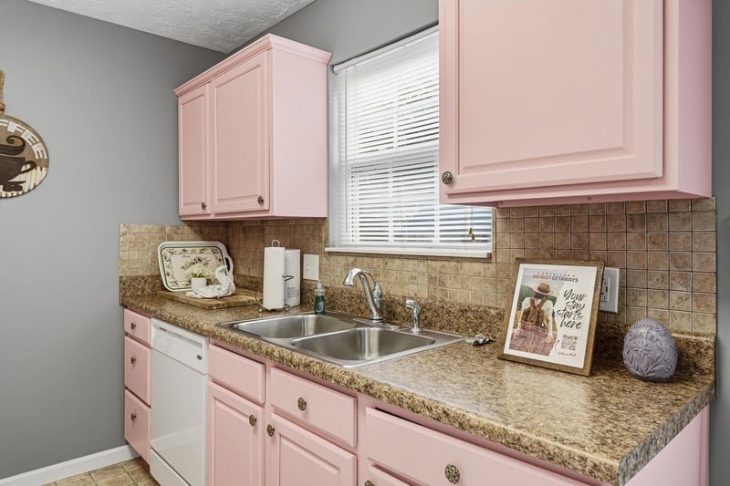 Your charming pink kitchen awaits with granite counters, double sink, and cheerful touches for memorable cooking moments.