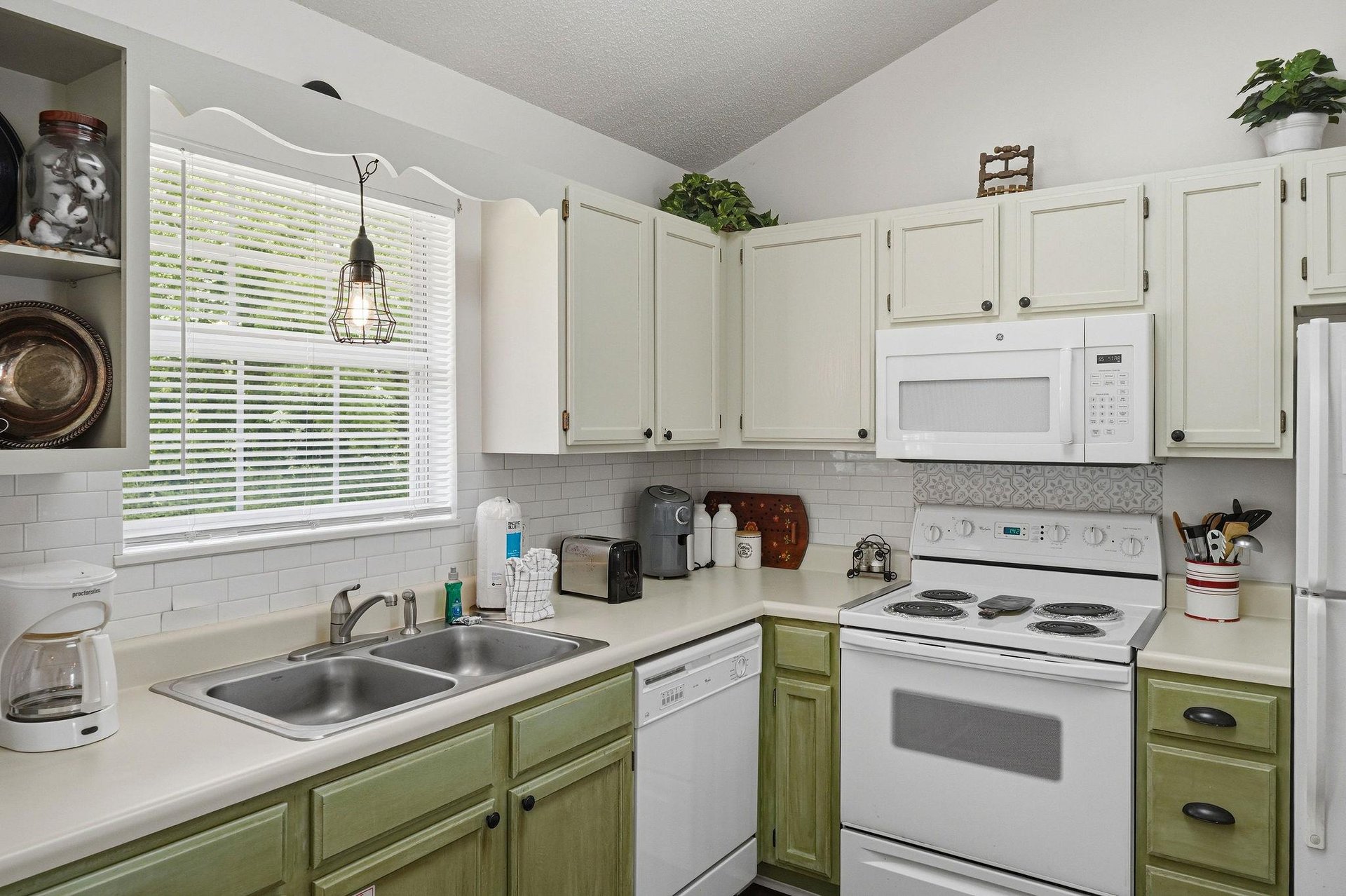 Picture yourself brewing morning coffee in your fully equipped kitchen, where natural light streams through the window, highlighting the charming twotone cabinetry and modern appliances ready for you