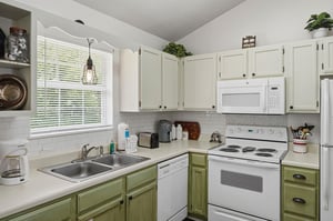 Picture yourself brewing morning coffee in your fully equipped kitchen, where natural light streams through the window, highlighting the charming twotone cabinetry and modern appliances ready for you