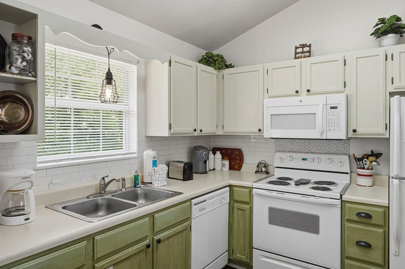 Picture yourself brewing morning coffee in your fully equipped kitchen, where natural light streams through the window, highlighting the charming twotone cabinetry and modern appliances ready for you