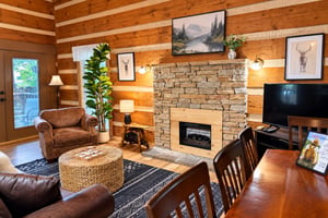 Step into your cozy mountain retreat with warm log walls, a stunning stone fireplace, and inviting leather seating. Natural light streams in, highlighting rustic charm perfect for your relaxing getawa