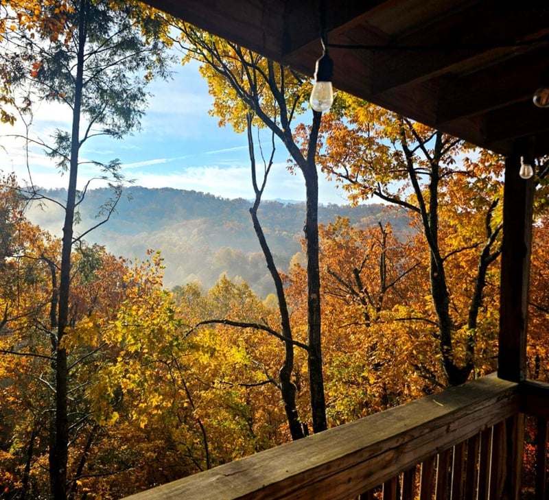 Mountain retreat framed by vibrant autumn foliage, offering sweeping views of layered ridges and colorful fall trees from your private covered balcony.