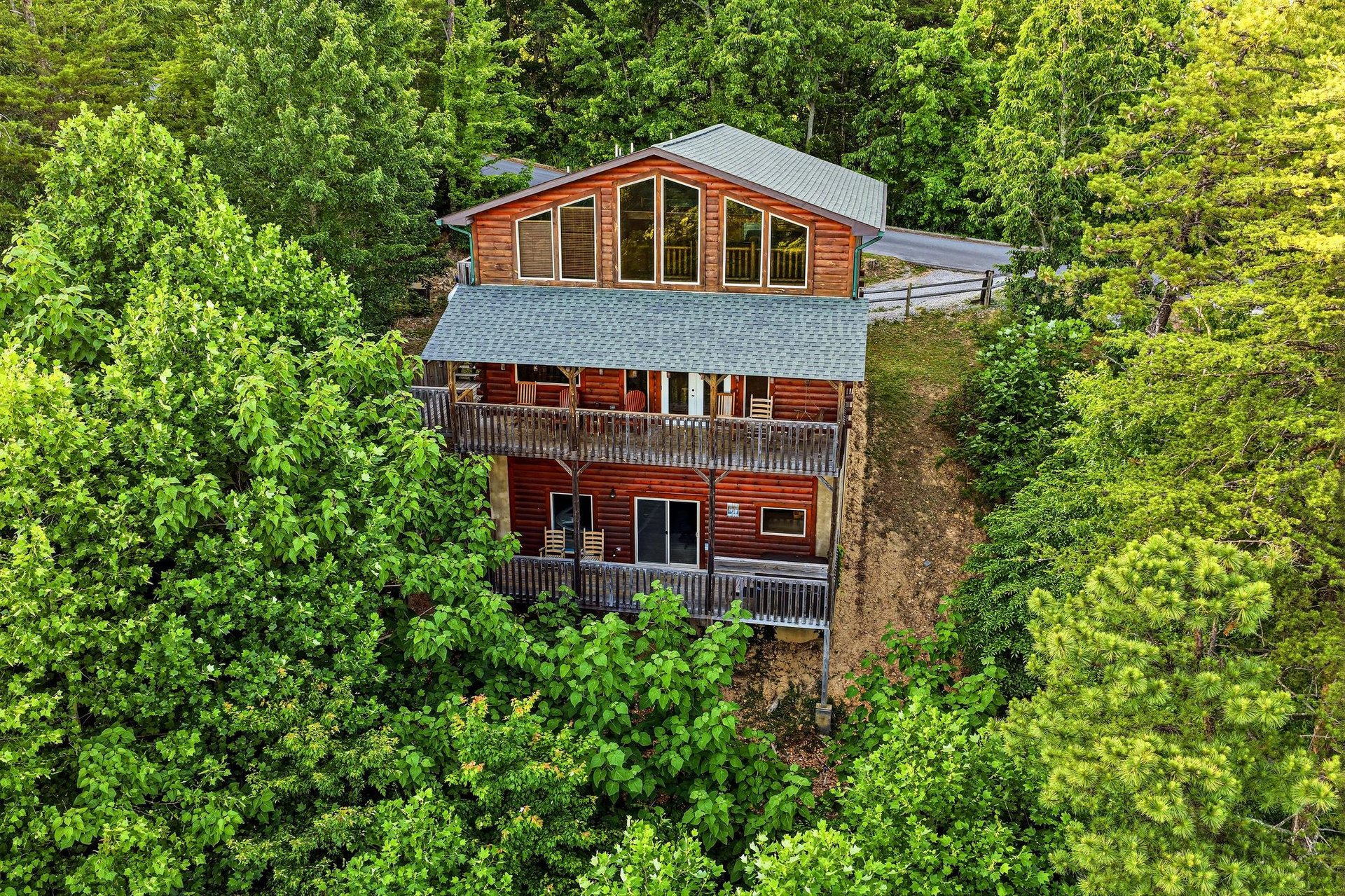 A stunning threestory cabin nestled in a lush forest, featuring expansive windows, spacious balconies, and a unique architectural design perfect for a secluded mountain retreat.