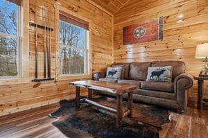 Cozy up in your rustic living room with warm wood walls, leather seating, and charming elkthemed pillows.