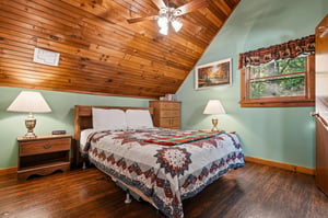 Your cozy bedroom retreat features warm wood ceilings, soft bedside lighting, and beautiful quilt bedding for peaceful nights.