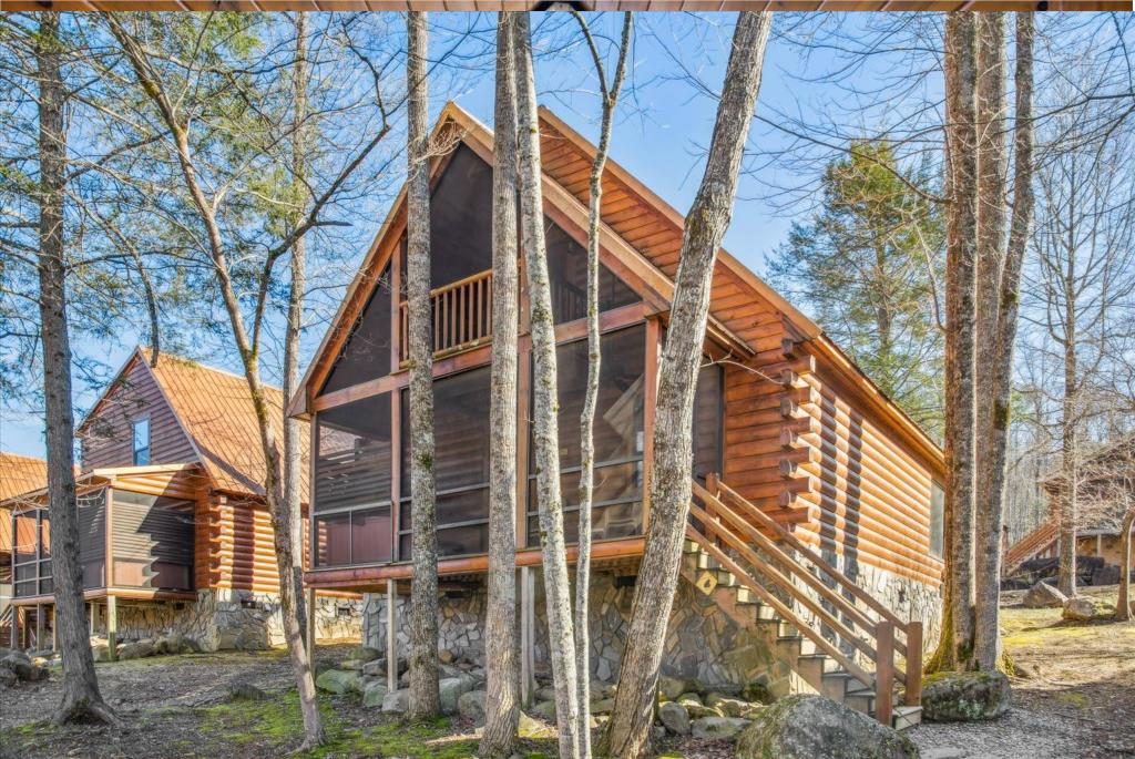 Modern log cabin nestled among tall trees, featuring warm wood siding and large windows for natural light.