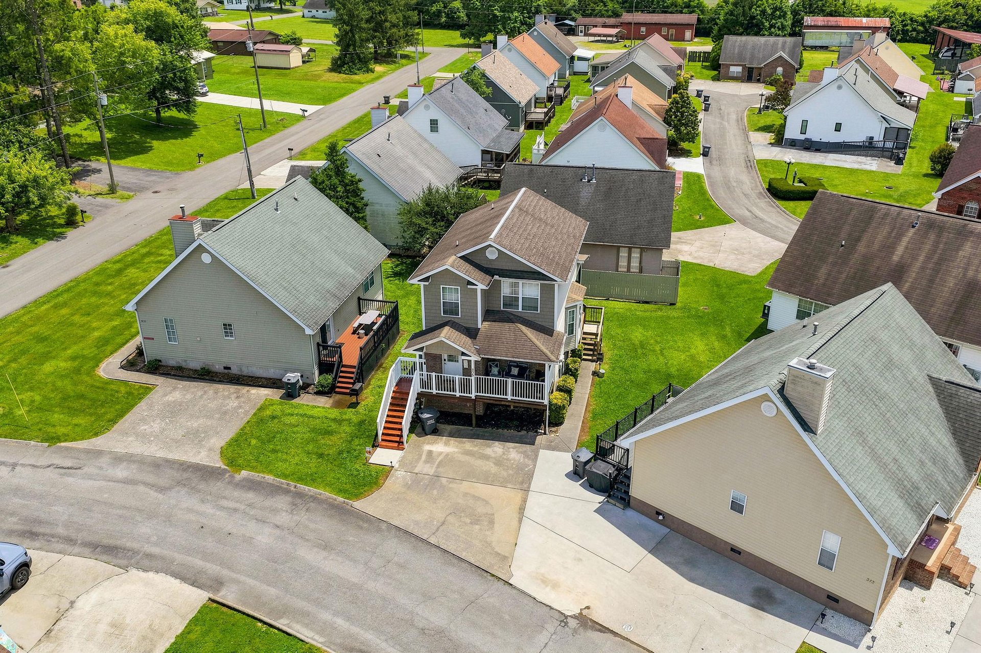 Aerial view of a peaceful residential neighborhood featuring wellmaintained vacation rental properties with spacious lawns, treelined streets, and convenient parking areas.