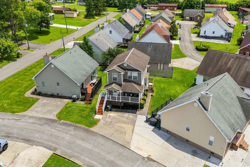 Aerial view of a peaceful residential neighborhood featuring wellmaintained vacation rental properties with spacious lawns, treelined streets, and convenient parking areas.
