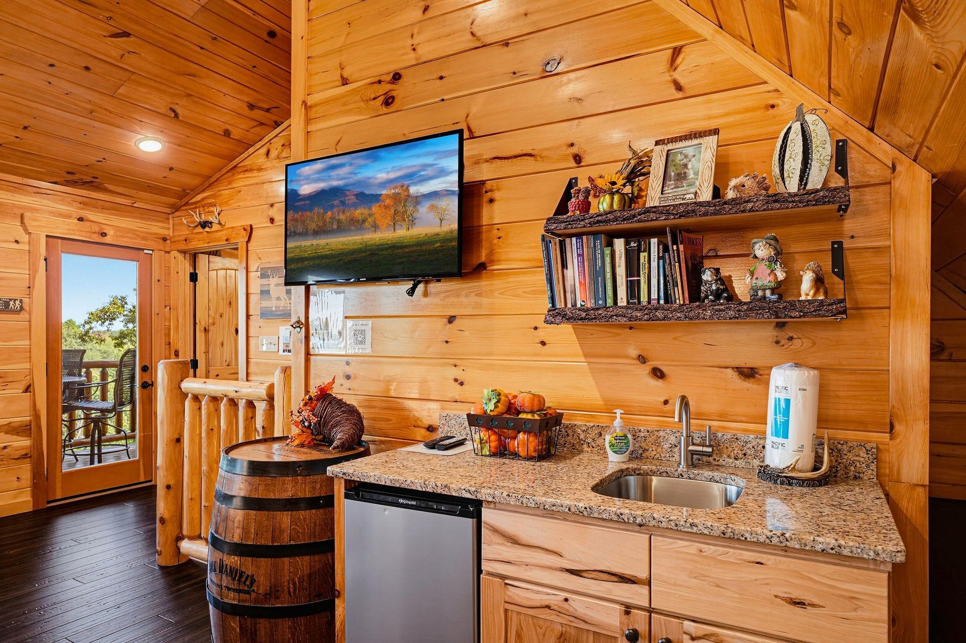 Warm wood surrounds you in this cozy kitchenette, complete with granite counters, a mini fridge, and rustic touches like a barrel table and handmade shelves stocked with books and decor.
