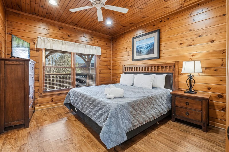 Unwind in your cozy bedroom featuring warm wood paneling, a plush bed, and a ceiling fan to keep you comfortable yearround. Fresh towels and peaceful natural light complete the relaxing retreat.