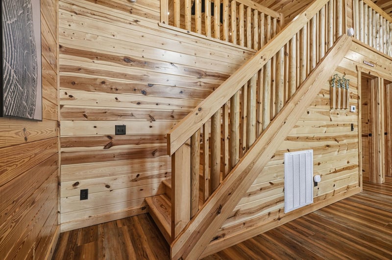Enjoy the warmth and character of this allwood interior, where natural grain and rustic craftsmanship surround you. A cozy staircase invites you upstairs, blending function with charm throughout your