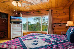 Wake up to treelined views framed by expansive windows in this cozy logwalled bedroom. Rest easy beneath a colorful quilt and enjoy the peaceful mountain atmosphere all around you.