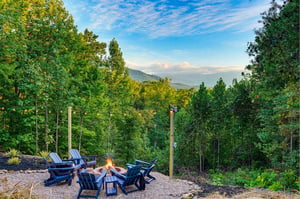 A fire pit on the property surrounded by Adirondack chairs, set against a natural mountain backdrop—an ideal spot for outdoor relaxation.