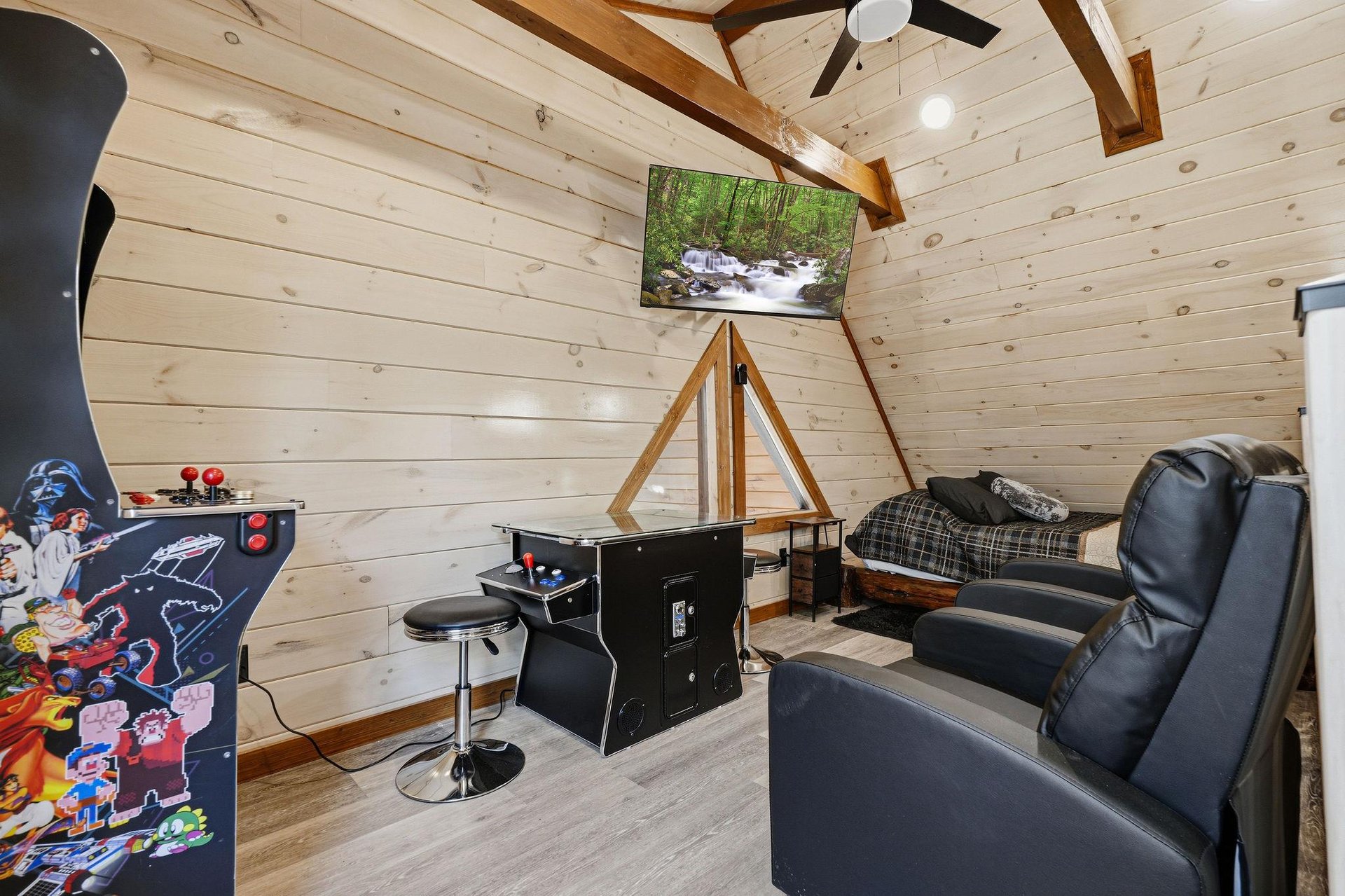 Unwind in your private game room featuring arcade games and cozy seating under rustic wooden beams.