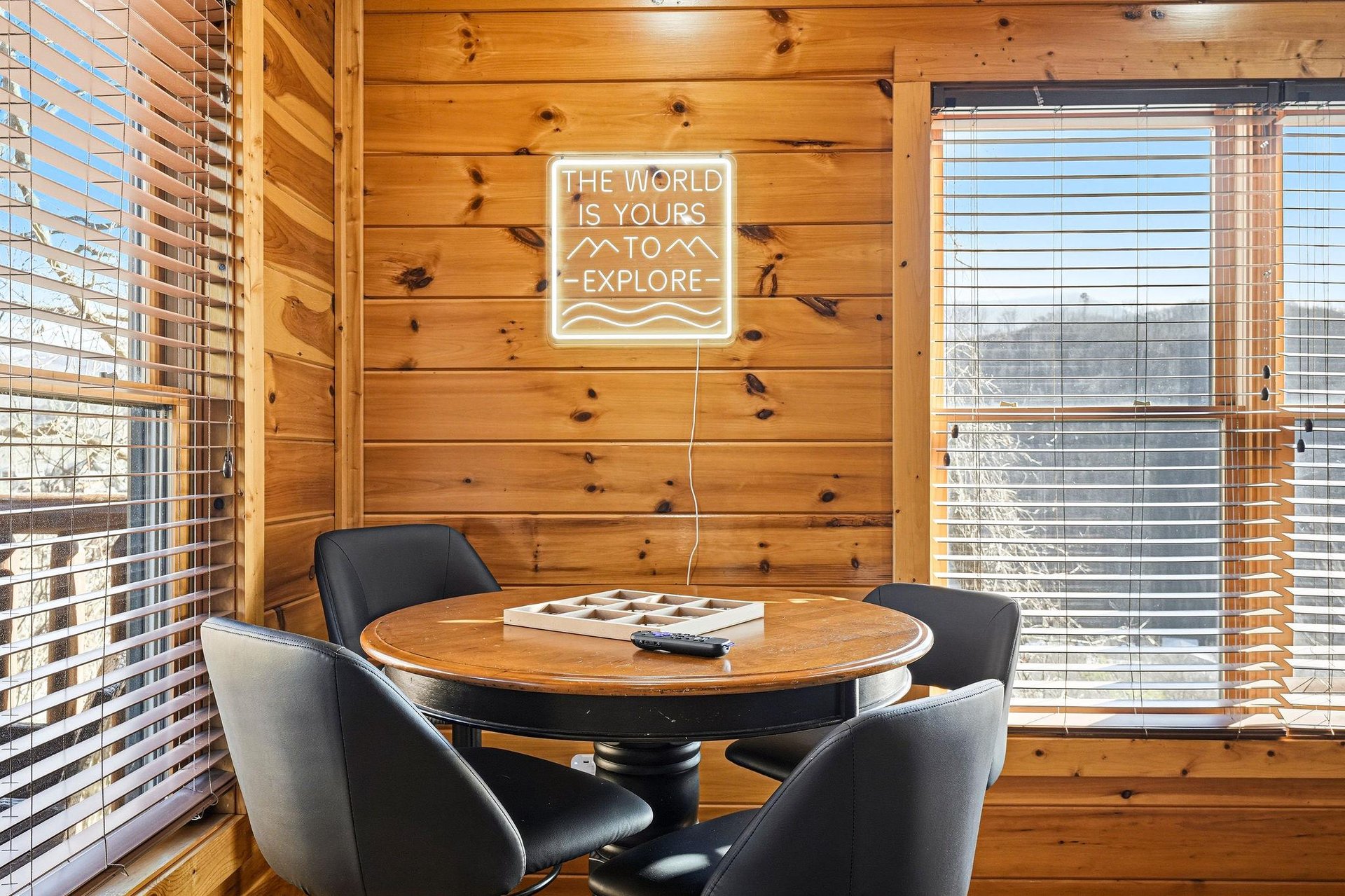 Gather around this cozy wooden corner with inspiring neon art, where your morning coffee conversations feel perfectly framed by natural light streaming through the blinds.