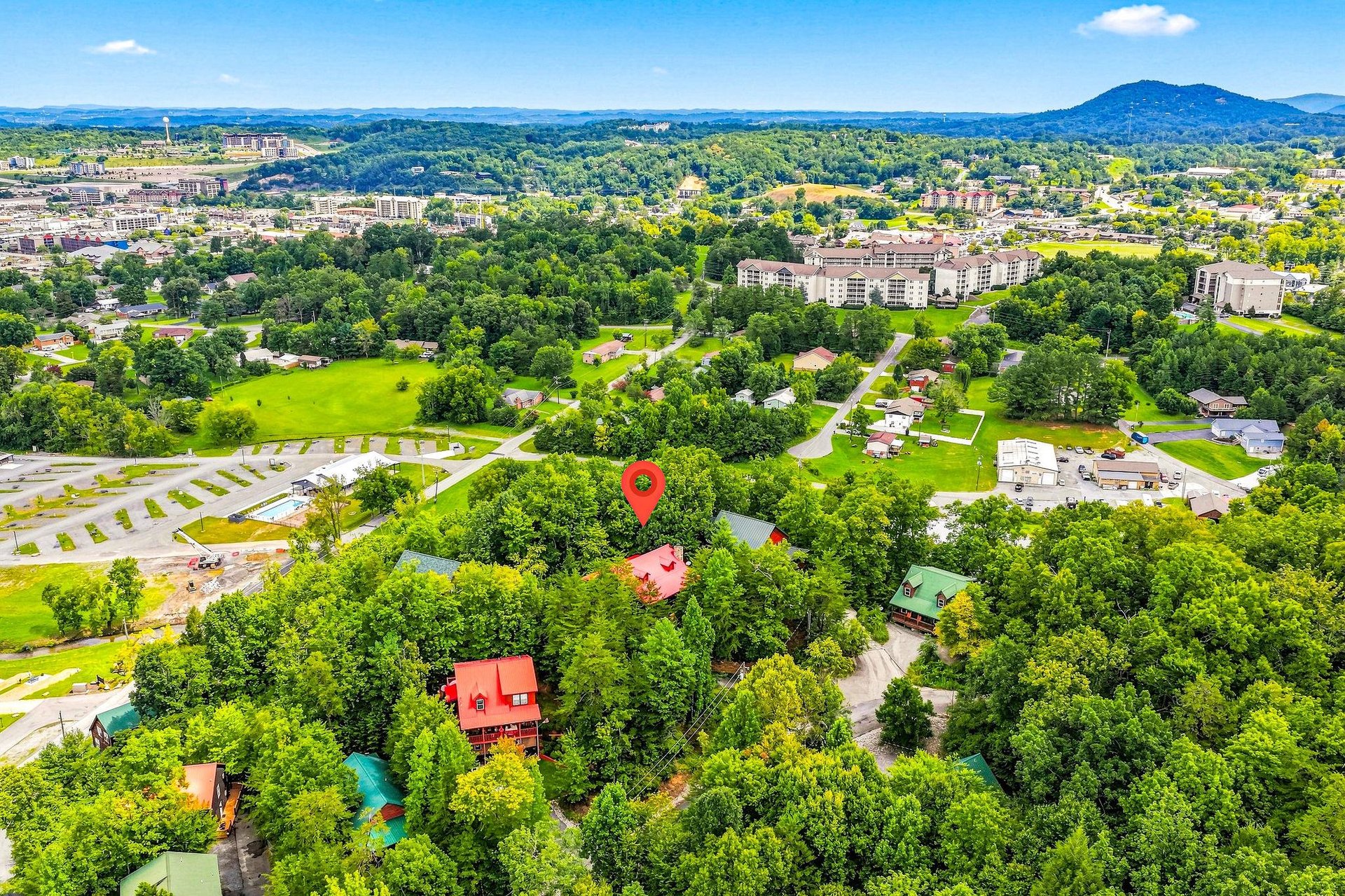 An aerial view captures the property nestled among lush greenery, with rolling mountains framing the vibrant community beyond.
