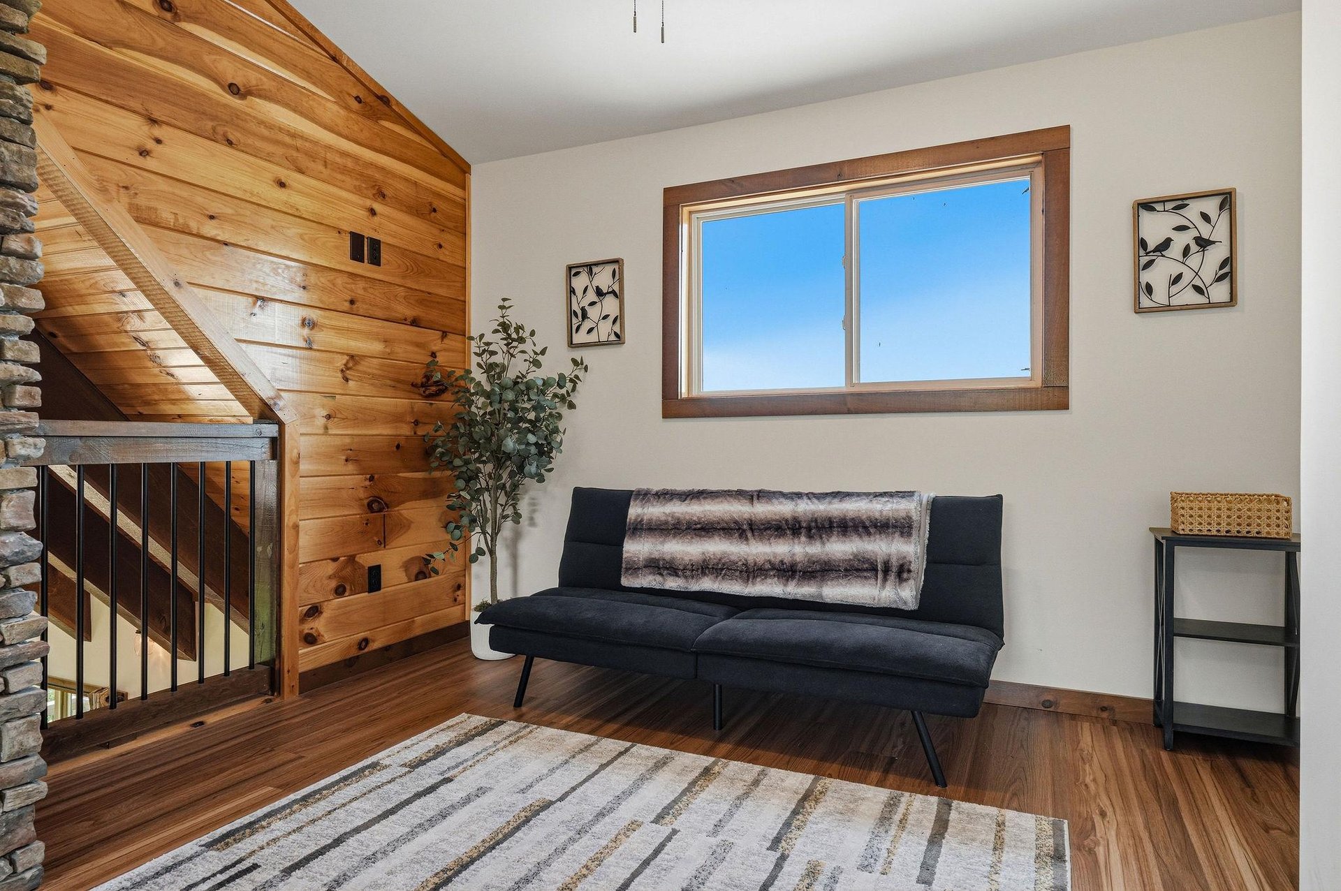 Settle into this bright loft seating area, where warm wood tones and a cozy sofa invite you to unwind. Natural light pours through the window, highlighting the cabinstyle charm that makes your mounta