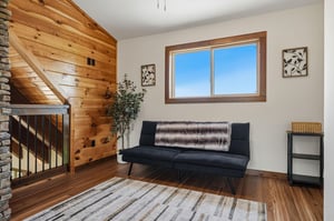 Settle into this bright loft seating area, where warm wood tones and a cozy sofa invite you to unwind. Natural light pours through the window, highlighting the cabinstyle charm that makes your mounta