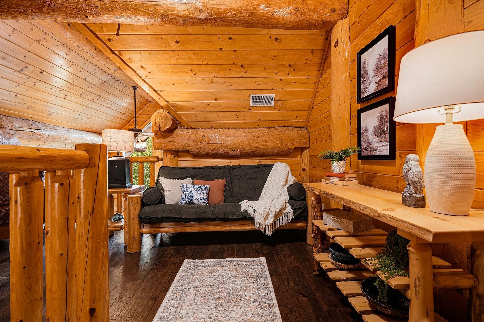 Step into your cozy log cabin retreat with warm wood walls, rustic log beams, and a comfy futon perfect for curling up after a day of exploring.