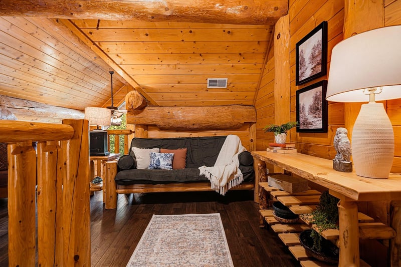 Step into your cozy log cabin retreat with warm wood walls, rustic log beams, and a comfy futon perfect for curling up after a day of exploring.