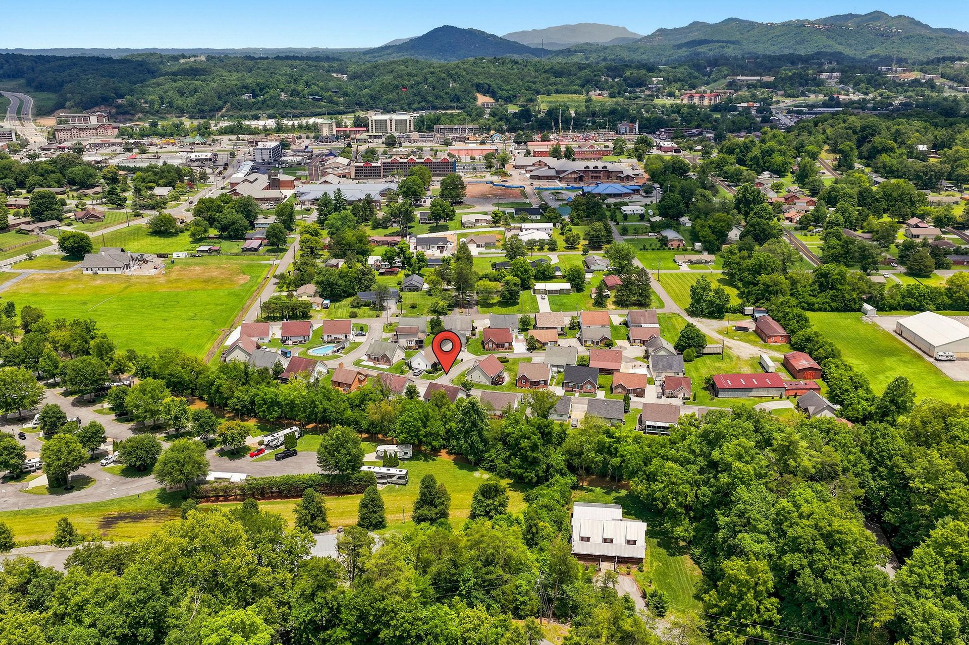 Aerial view of the propertys location in a peaceful residential neighborhood, with scenic mountain ranges and lush greenery surrounding the area.