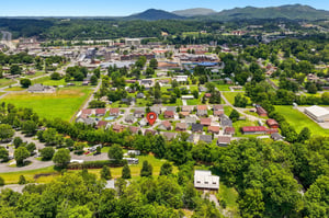Aerial view of the propertys location in a peaceful residential neighborhood, with scenic mountain ranges and lush greenery surrounding the area.