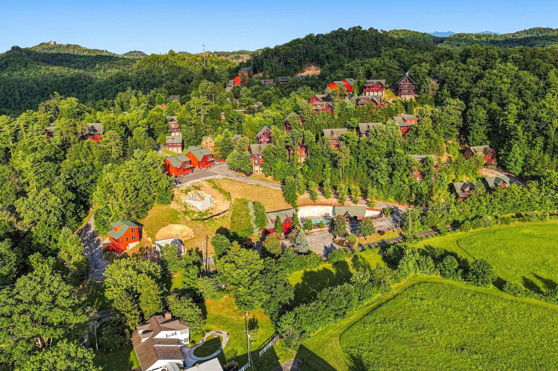 Aerial view of the property nestled in a lush, forested mountainside with redroofed buildings and green surroundings defining the neighborhood and natural landscape.