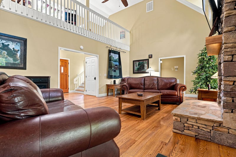Stretch out on plush leather sofas in your spacious living room, where soaring ceilings, warm wood floors, and a striking stone fireplace create the perfect setting for relaxation and togetherness.