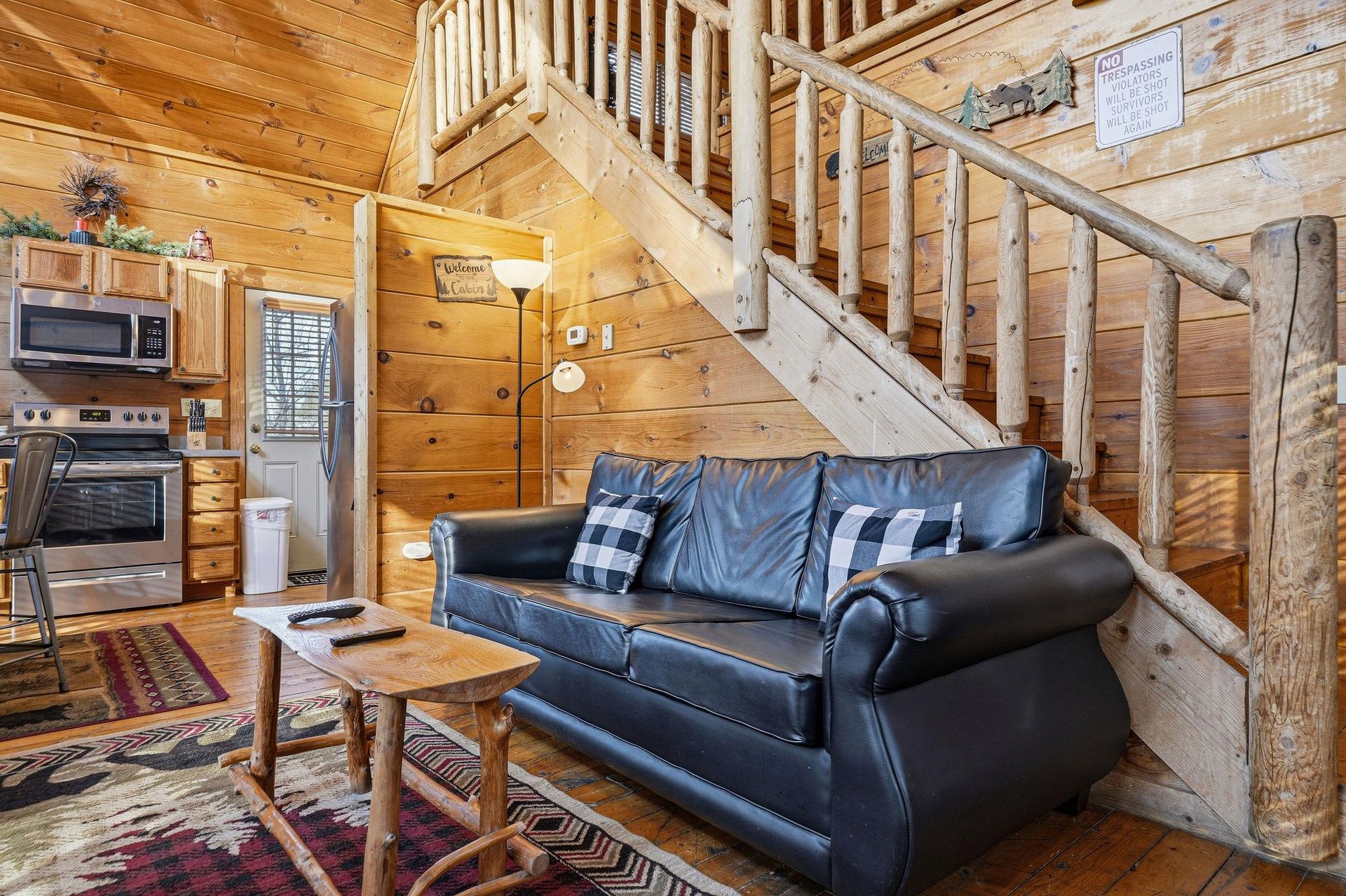 Unwind on the leather sofa beneath rustic log stairs in your cozy cabin retreat.