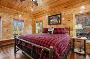 Snuggle into your cozy log cabin bedroom with rustic charm, plaid bedding, and forest views from every window.