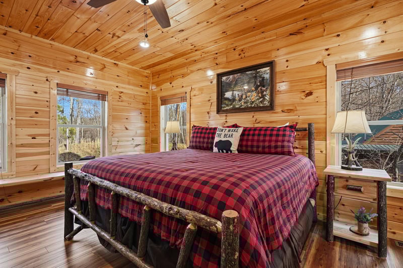 Snuggle into your cozy log cabin bedroom with rustic charm, plaid bedding, and forest views from every window.