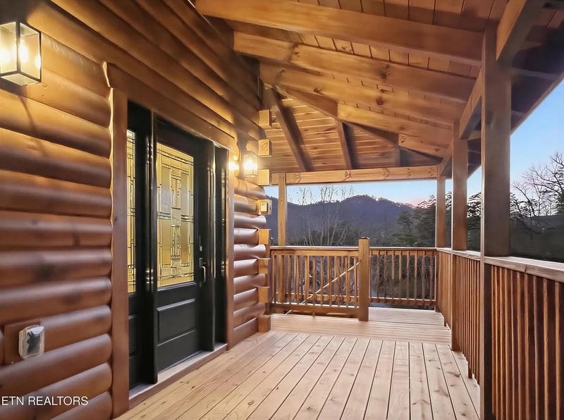 Step onto your private deck where mountain vistas await, framed by rustic log beams and peaceful evening light.