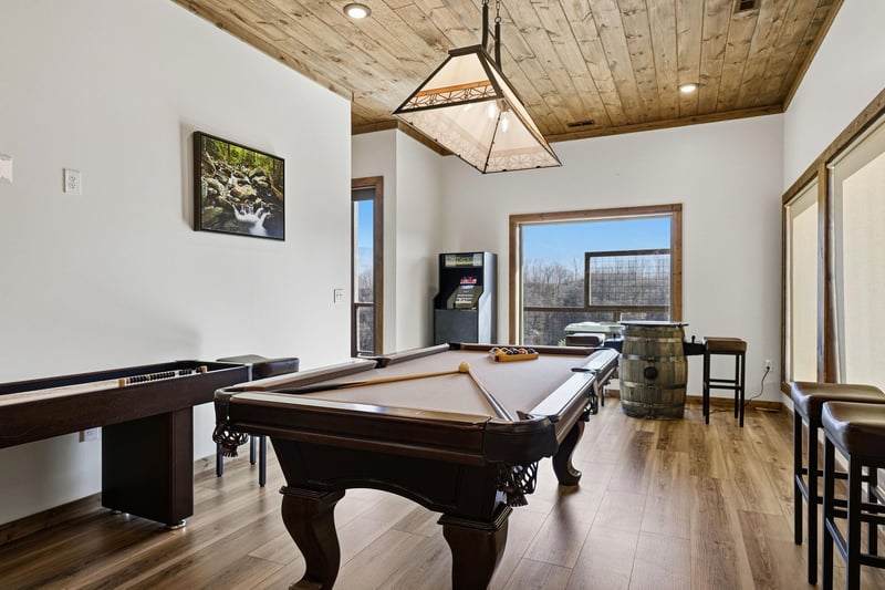 Challenge friends to pool or unwind with mountain views in your private game room featuring rustic wood ceilings.