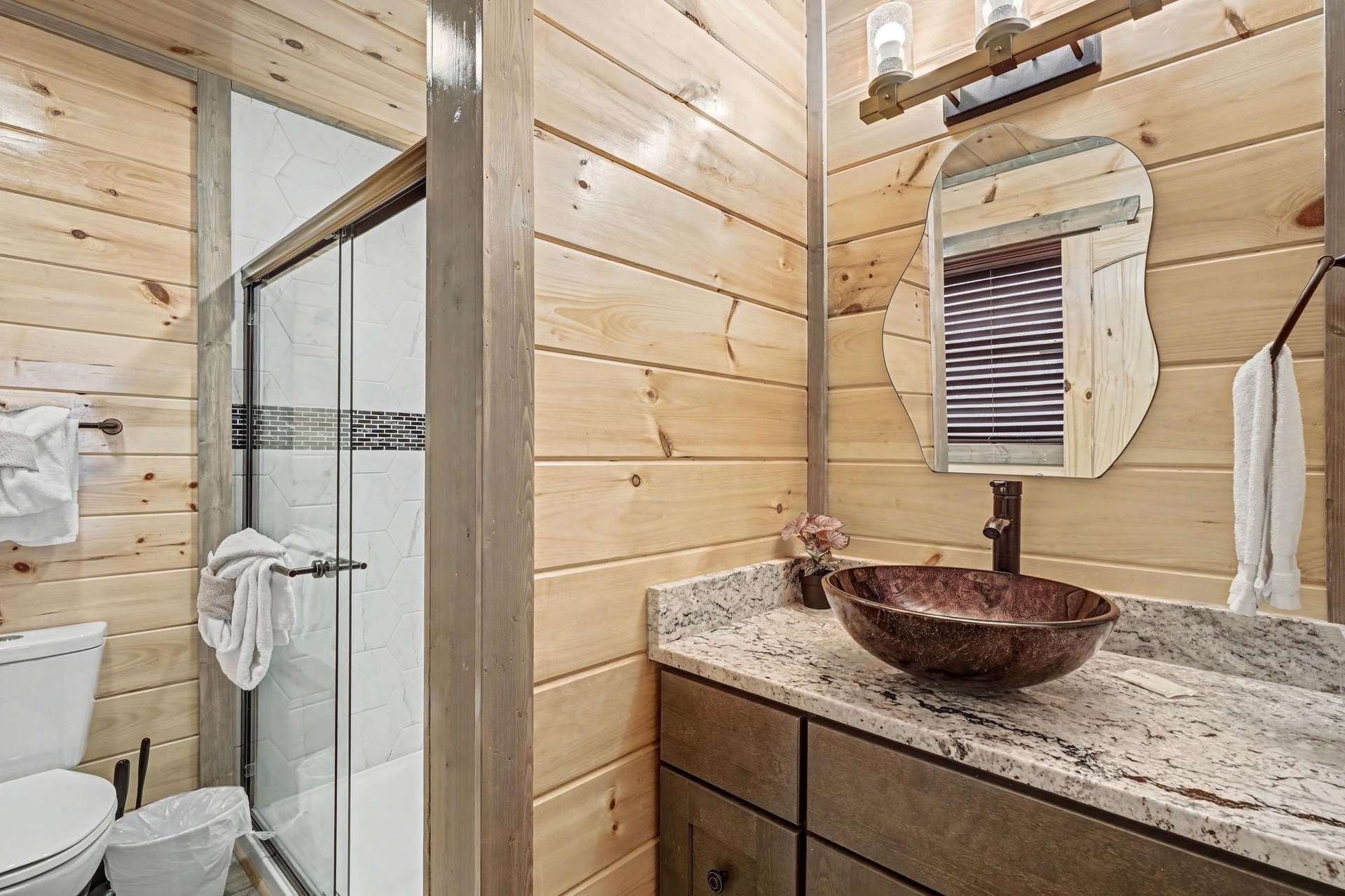 Rustic elegance meets modern comfort in your private bathroom, featuring warm wood walls and a stunning vessel sink.