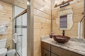 Rustic elegance meets modern comfort in your private bathroom, featuring warm wood walls and a stunning vessel sink.