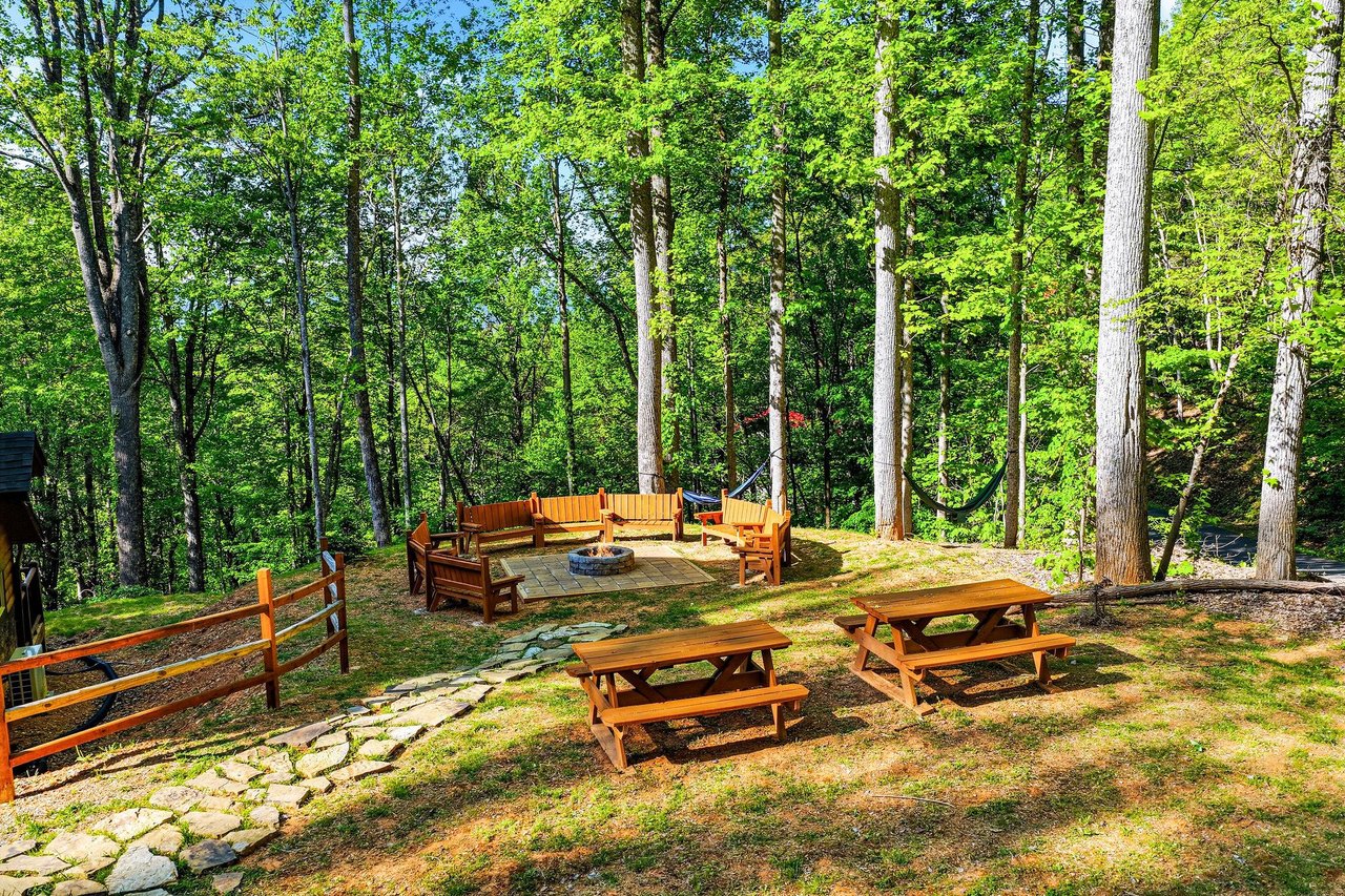 Gather around the fire pit for smores under towering trees, with picnic tables perfect for outdoor dining in this peaceful forest setting.