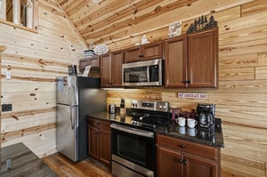 Your cabin kitchen blends rustic charm with modern convenience, featuring stainless appliances, rich wood cabinetry, and a cozy hot chocolate bar ready for mountain mornings.