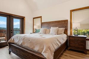 Wake up to breathtaking mountain vistas framed by your private balcony. This serene bedroom features warm wood tones, plush bedding, and plenty of natural light to start your day refreshed.