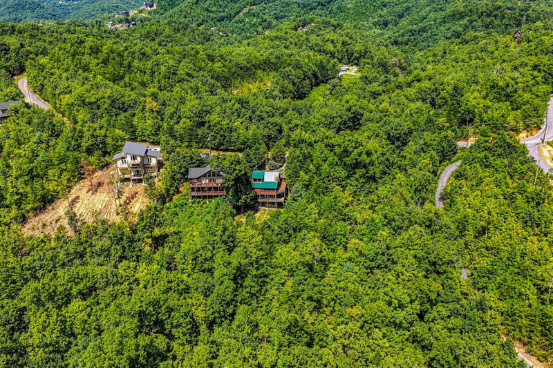 Aerial view of the property nestled among lush forested mountains, offering a serene mountain retreat setting surrounded by natural landscape and winding roads.