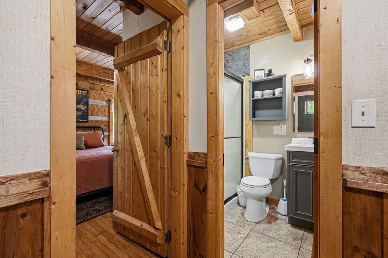 Step into rustic charm with warm wooden finishes throughout. Your private bathroom features modern fixtures and clever storage, while the cozy bedroom awaits just beyond the handcrafted barn door.
