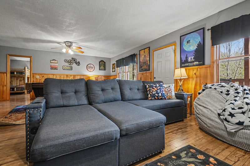Sink into your spacious sectional sofa and unwind in this cozy living room, where rustic wood paneling meets modern comfort for perfect relaxation.
