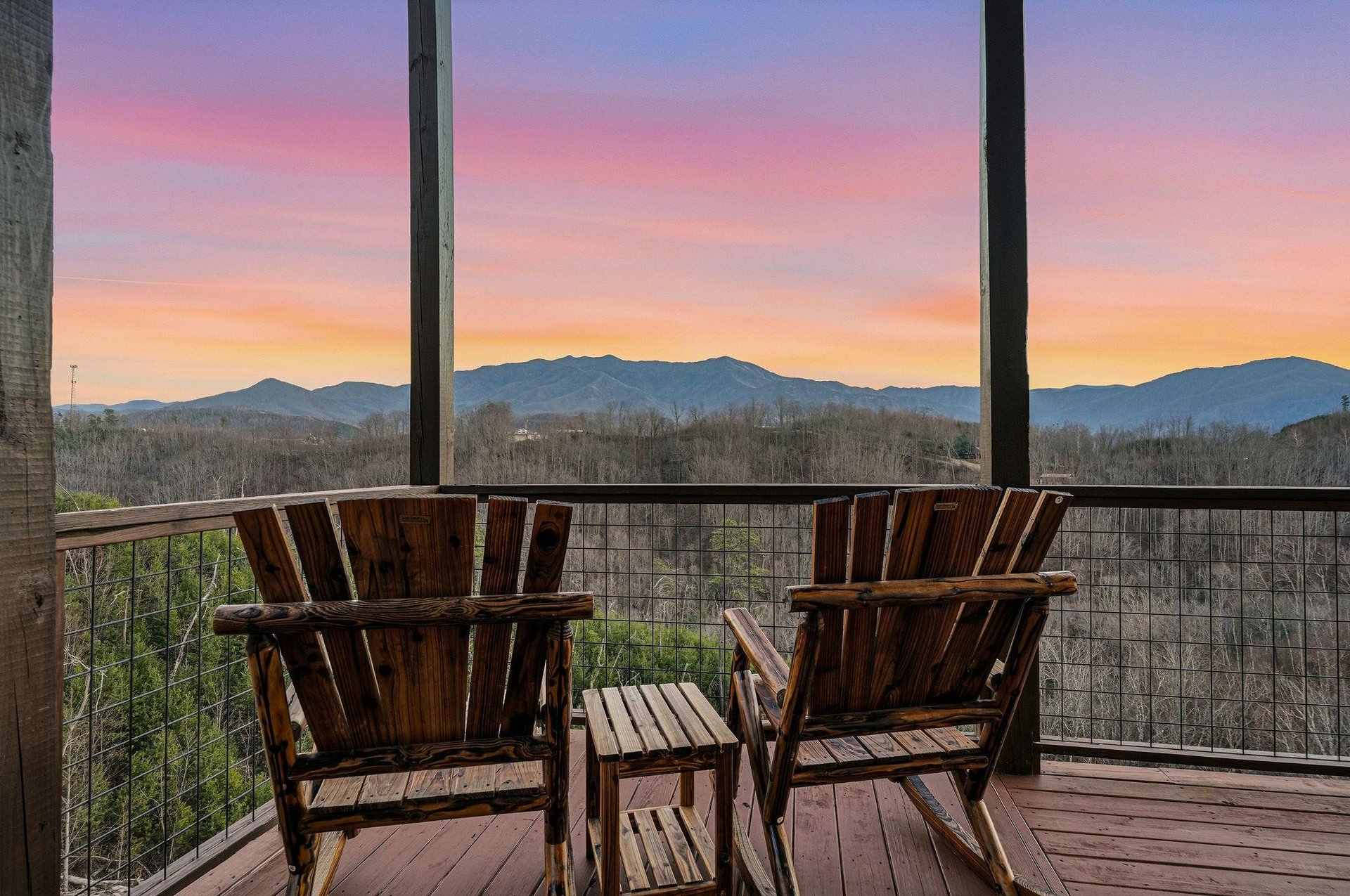 Mountain sunset paints the sky in brilliant colors beyond the balcony, creating a stunning backdrop for the surrounding landscape.