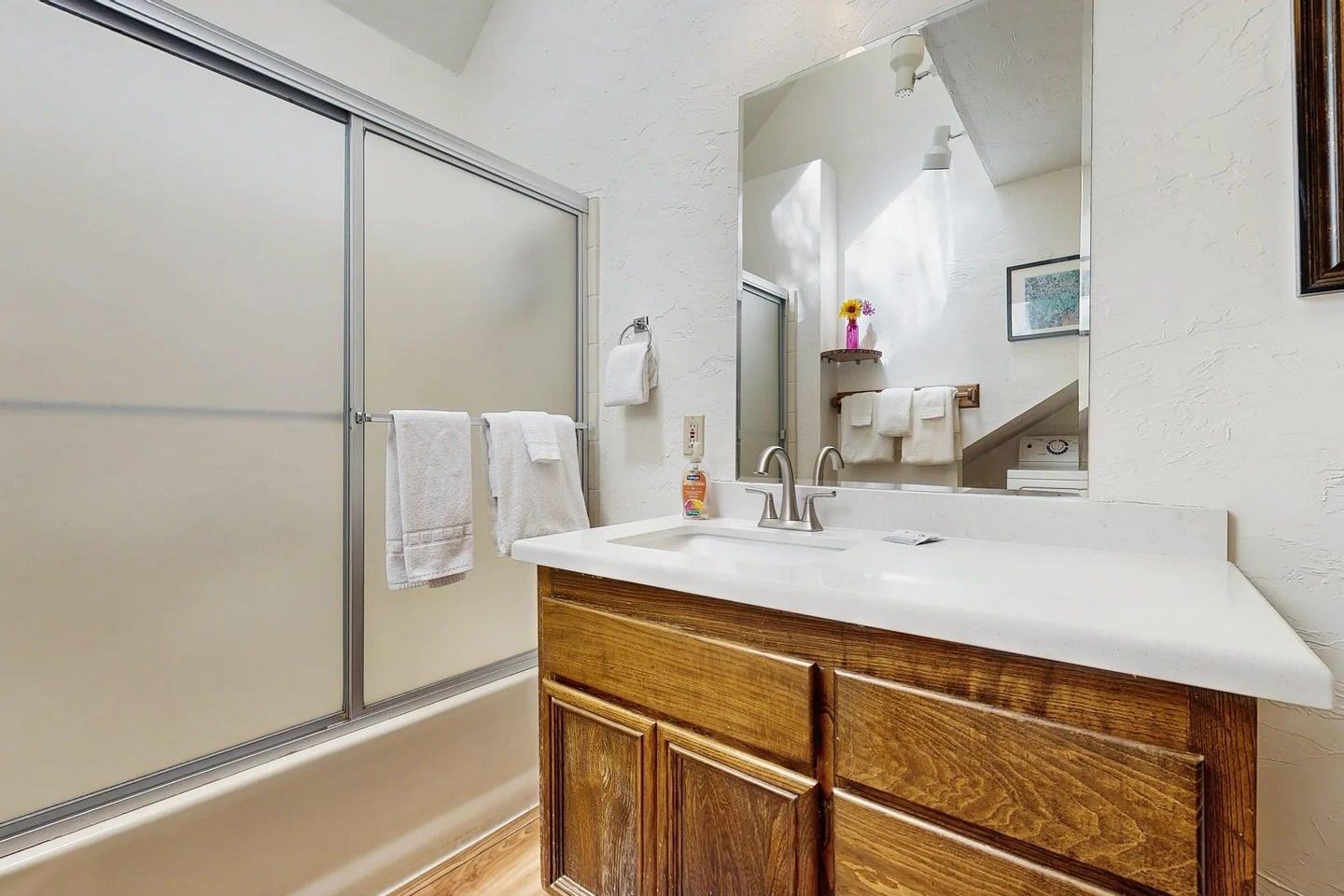 The mainfloor bathroom features a glassenclosed shower and a spacious vanity, conveniently located near the third bedroom.