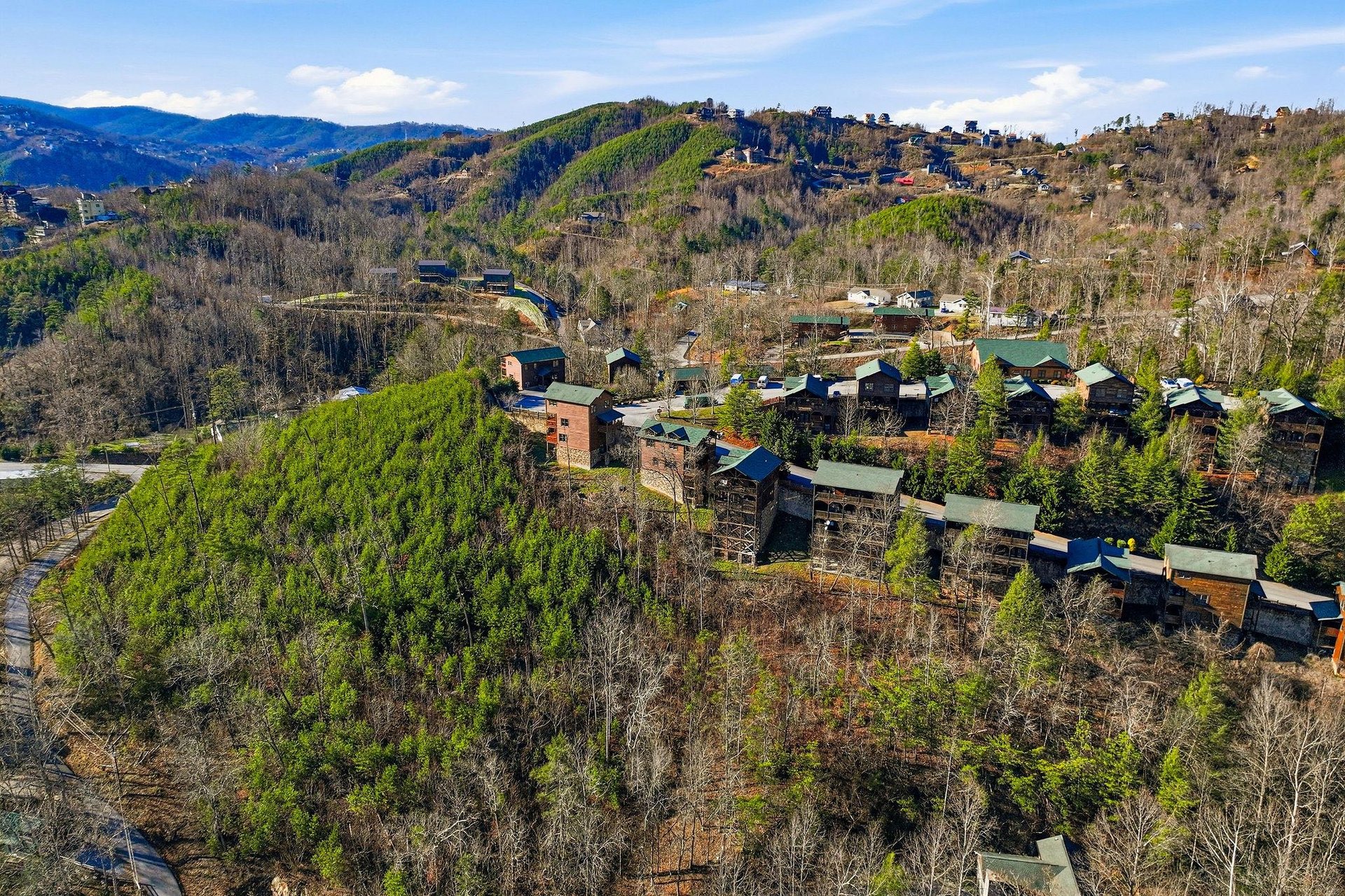 Aerial view showcasing a mountain resort community nestled among rolling hills and dense forest canopy.